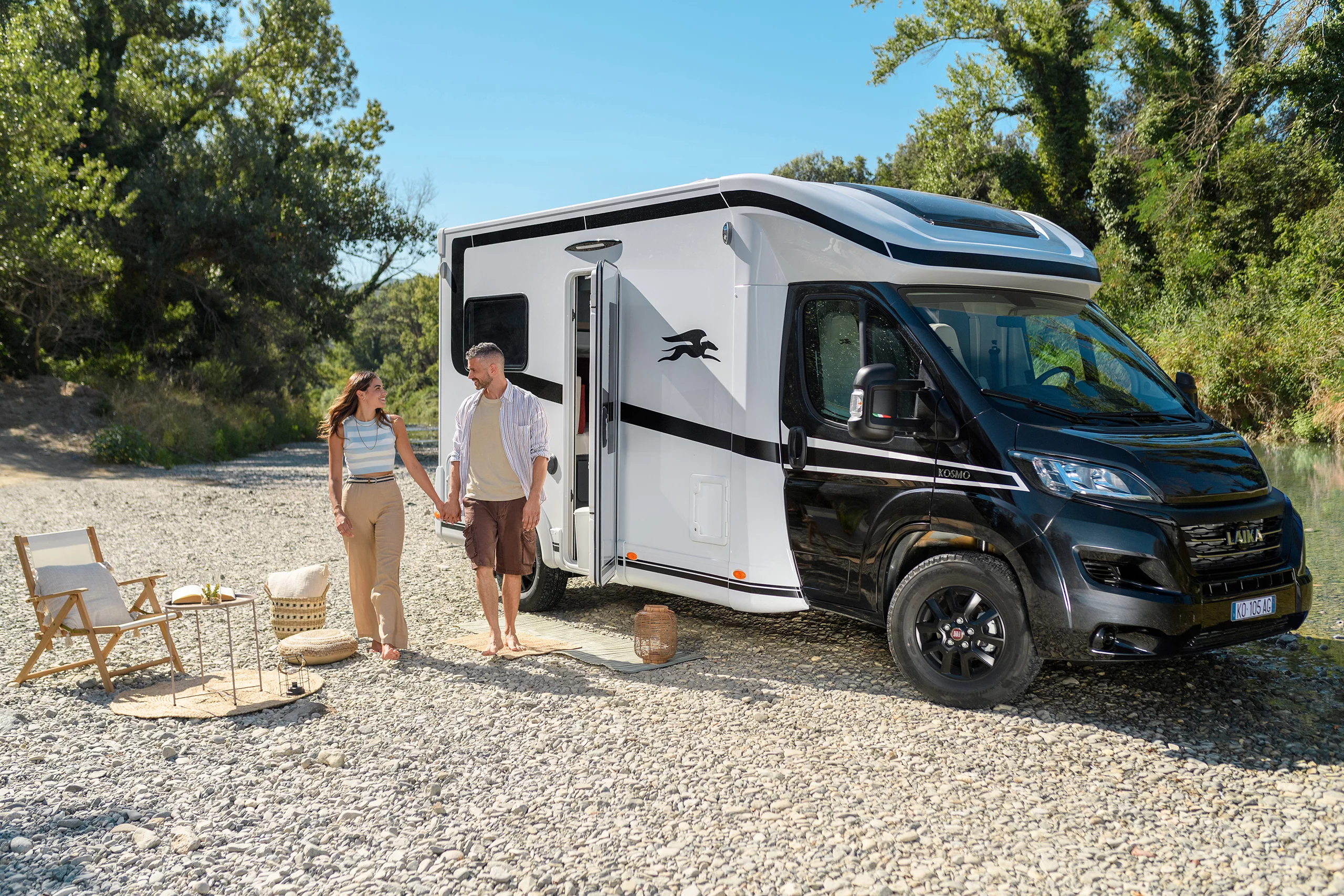 Camper van parked at riverside campsite with couple